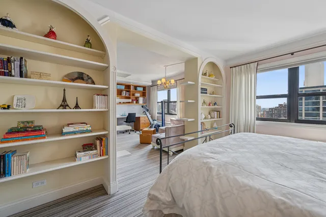 a bedroom with a bed a large window and book shelf
