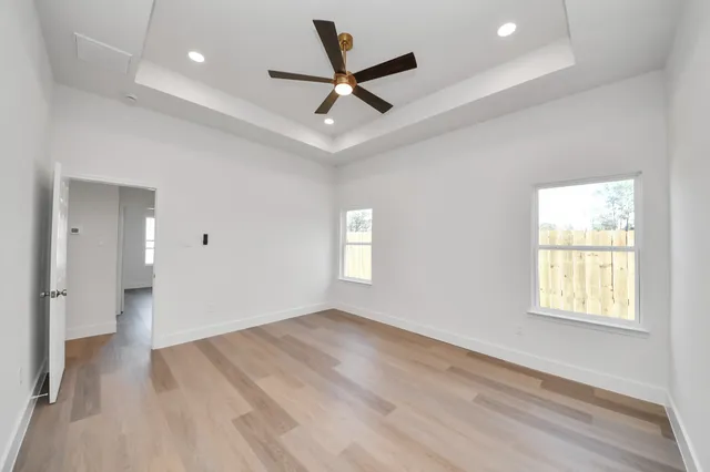 an empty room with wooden floor and windows