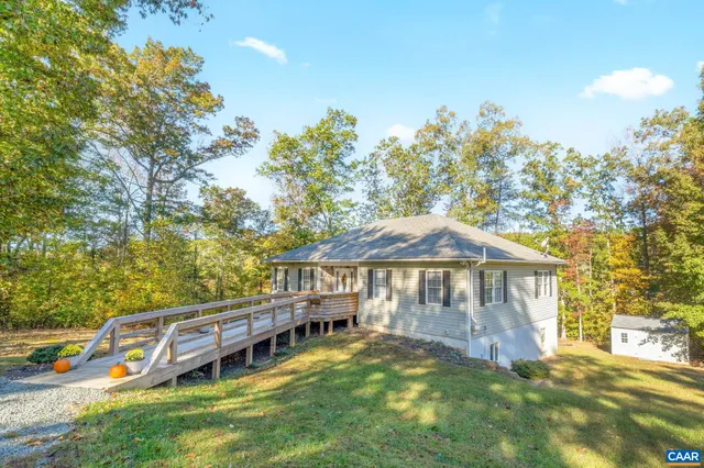 a front view of a house with a boat and large trees