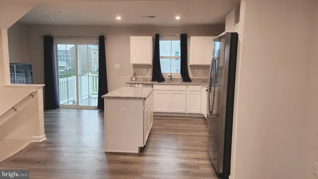 a kitchen with stainless steel appliances granite countertop a refrigerator a sink and a stove with wooden floor