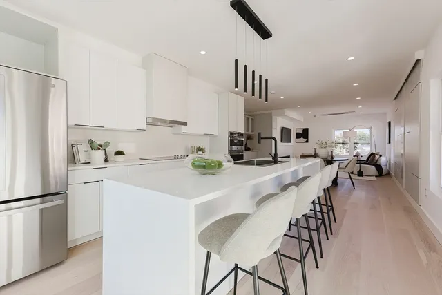 a kitchen with stainless steel appliances kitchen island granite countertop a refrigerator a stove a sink a dining table and chairs with wooden floor