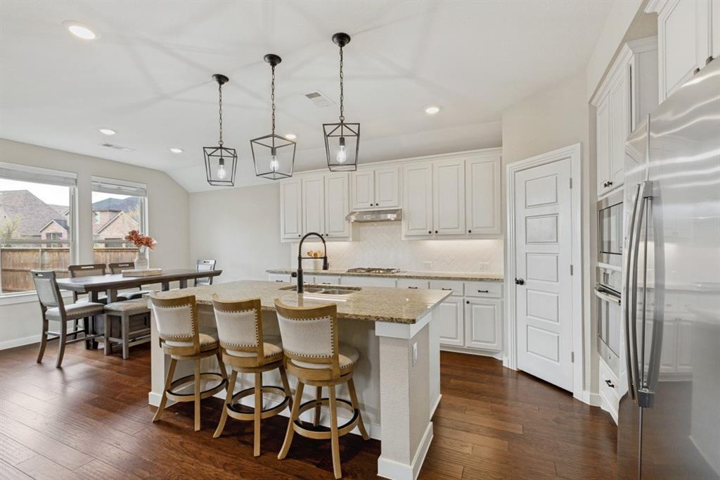 4136 Lightstone Lane Celina, TX 75009 - Photo 14 of 39 a kitchen with stainless steel appliances granite countertop a dining table chairs stove and white cabinets