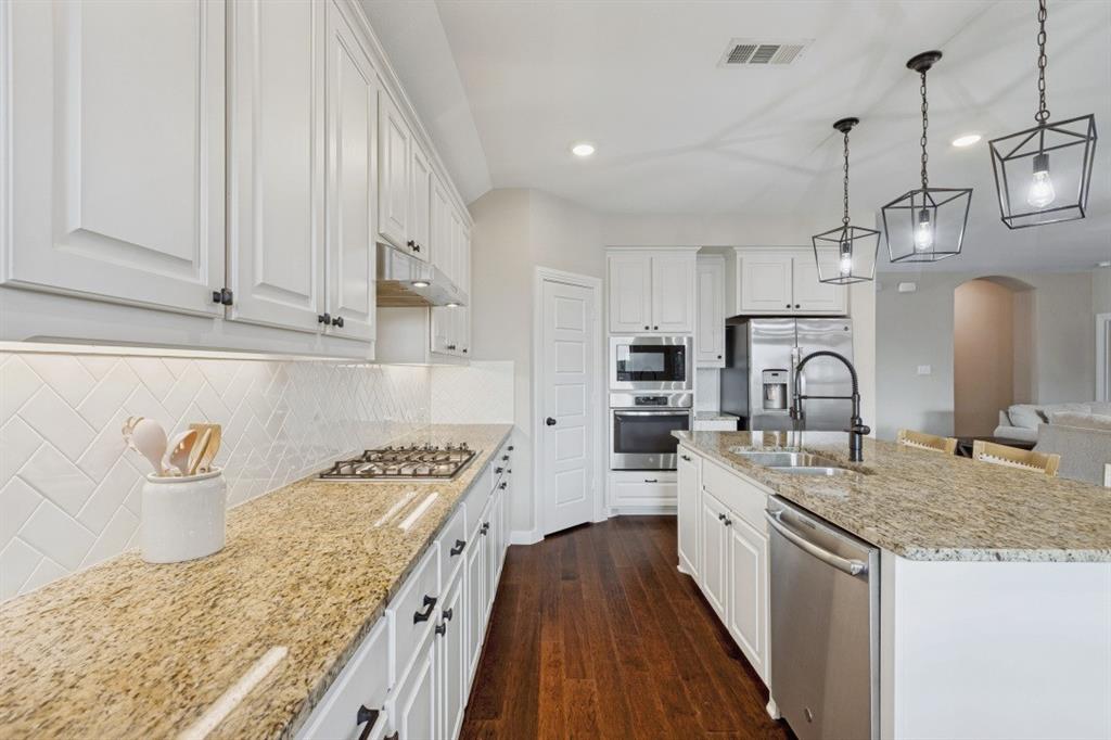 4136 Lightstone Lane Celina, TX 75009 - Photo 18 of 39 a kitchen with granite countertop a sink stove and cabinets