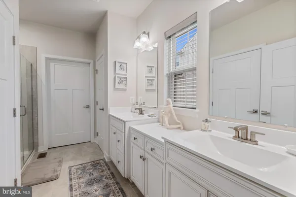 a spacious bathroom with double vanity a mirror and a shower