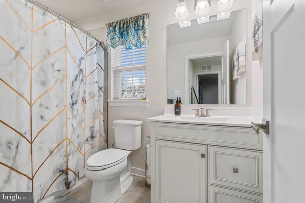 a bathroom with a granite countertop sink a toilet and a mirror