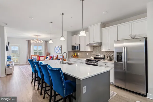 a kitchen with refrigerator a stove a sink a dining table and chairs
