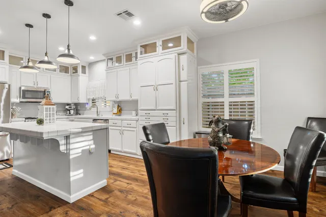 a kitchen with stainless steel appliances granite countertop a table chairs stove a sink dishwasher and cabinets