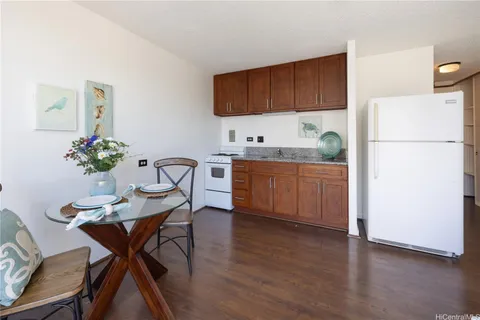 a kitchen with stainless steel appliances kitchen island granite countertop a dining table chairs and a refrigerator