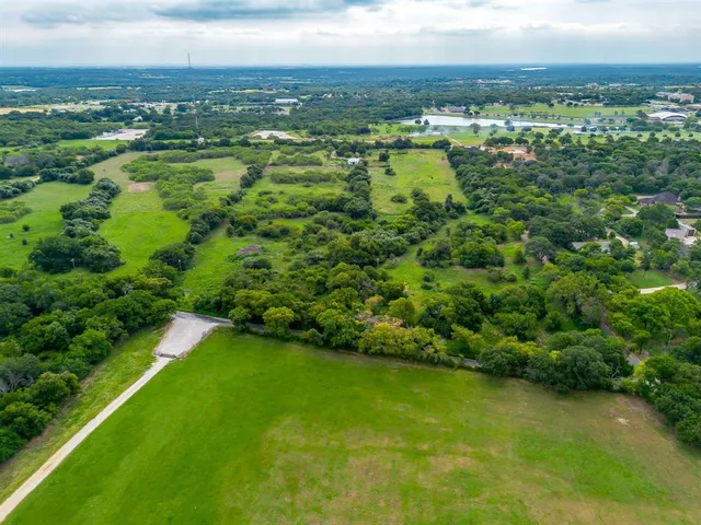 an aerial view of residential houses with outdoor space and trees