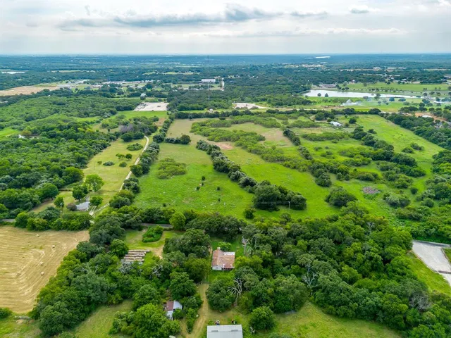 an aerial view of residential houses with outdoor space and trees