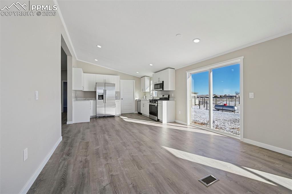 6315 Peerless Farms Road Peyton, CO 80831 - Photo 25 of 49 a view of a kitchen with wooden floor and a refrigerator