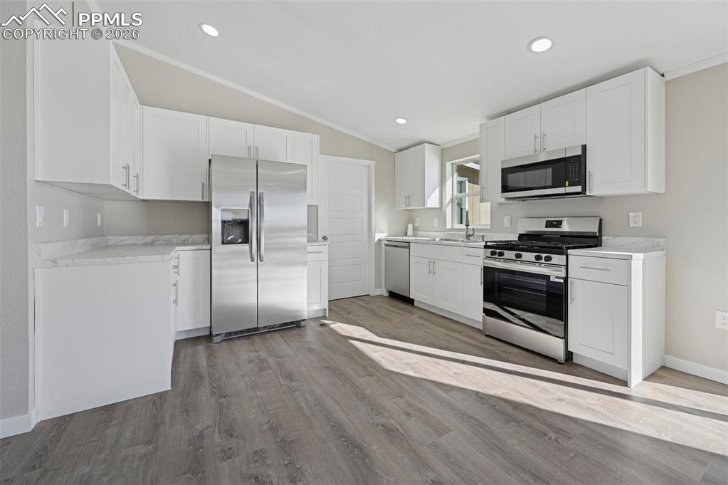 6315 Peerless Farms Road Peyton, CO 80831 - Photo 7 of 49 a kitchen with white cabinets and stainless steel appliances