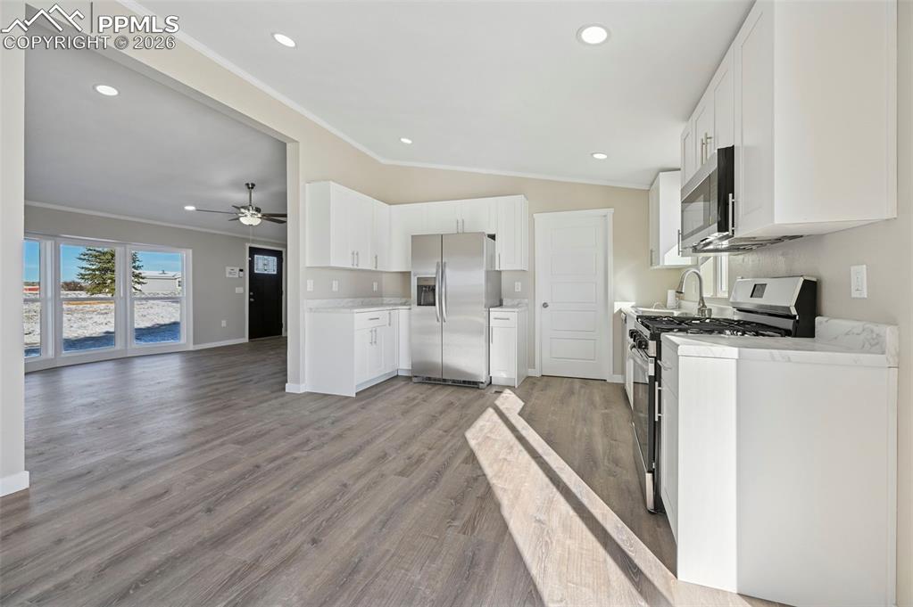 6315 Peerless Farms Road Peyton, CO 80831 - Photo 8 of 49 a kitchen with stainless steel appliances a refrigerator sink and cabinets