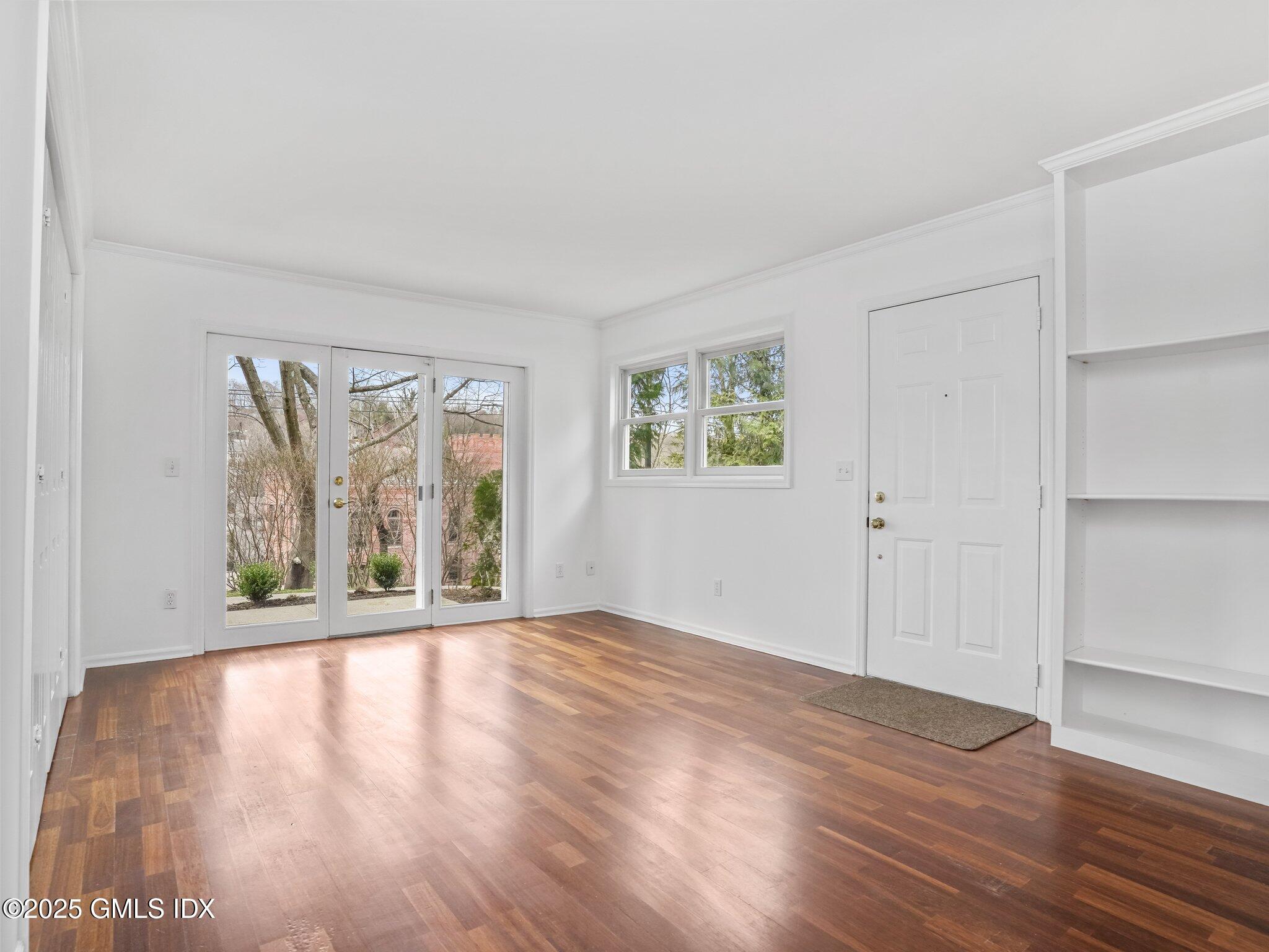 351 Pemberwick Road, Unit 205 Greenwich, CT 06831 - Photo 4 of 12 an empty room with wooden floor and windows