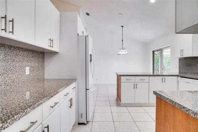 a kitchen with granite countertop a sink a counter top space and cabinets