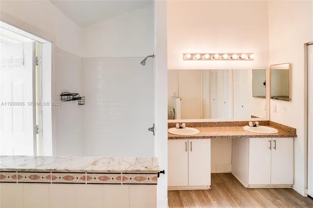 a bathroom with a granite countertop sink a mirror and a bathtub