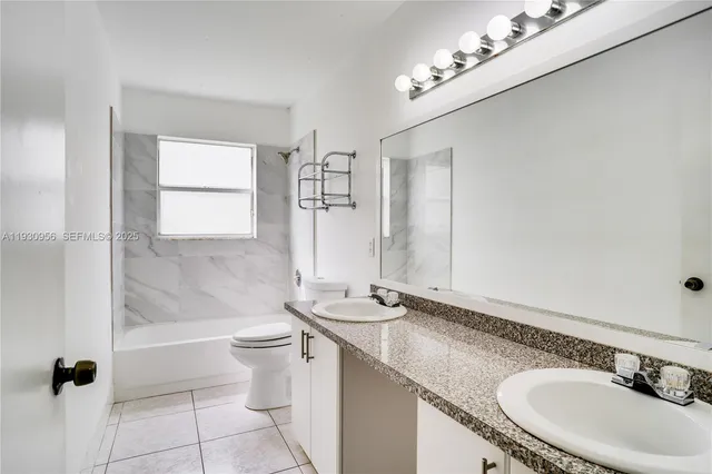 a bathroom with a granite countertop sink a toilet a mirror and shower