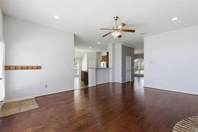 a view of an empty room with a kitchen and wooden floor