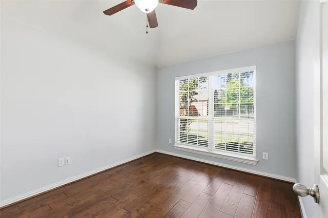 an empty room with wooden floor fan and windows