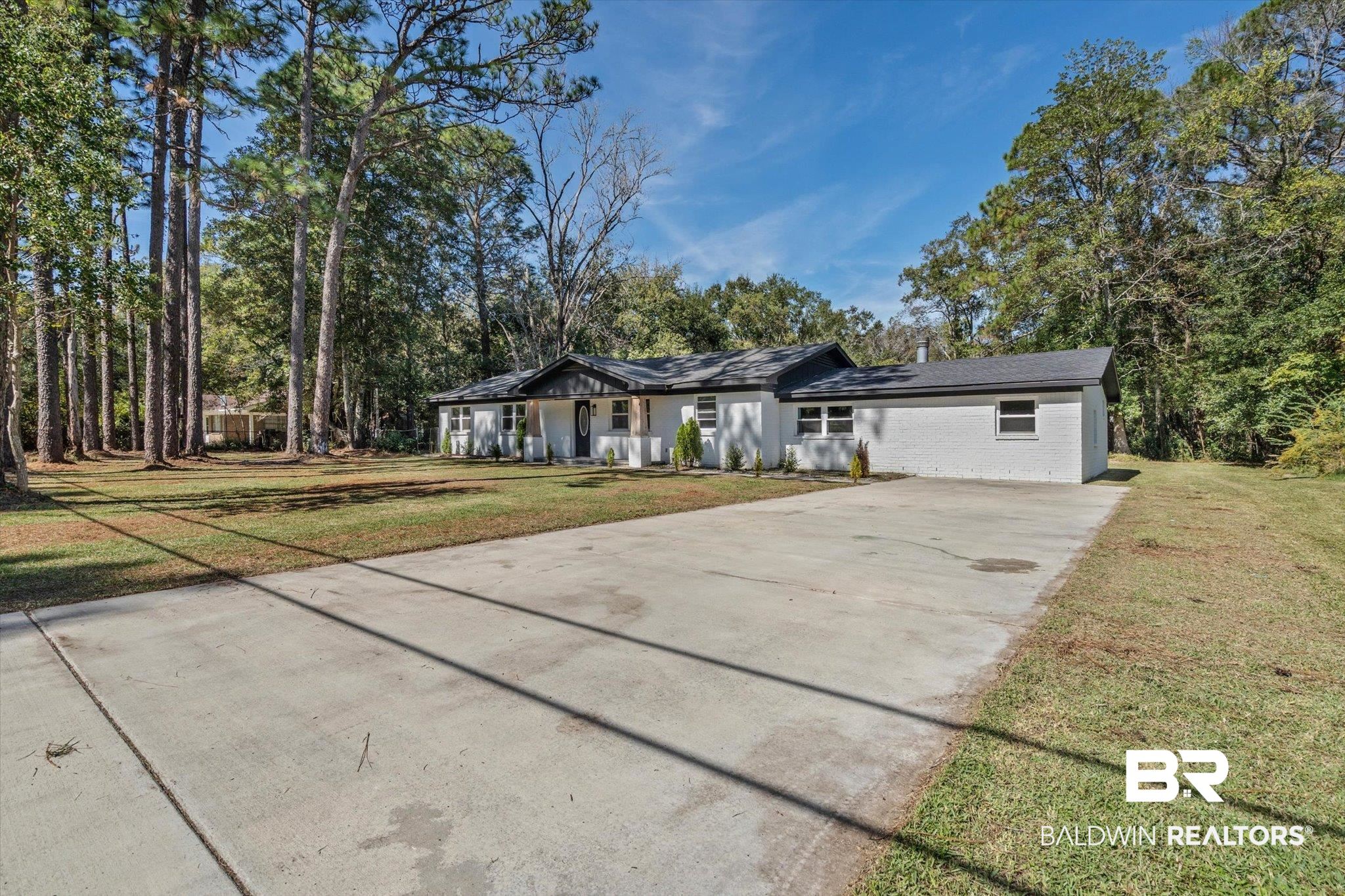 4156 Furman Drive Mobile, AL 36619 - Photo 22 of 24 Ranch-style home featuring a front lawn, concrete driveway, covered porch, and view of wooded area