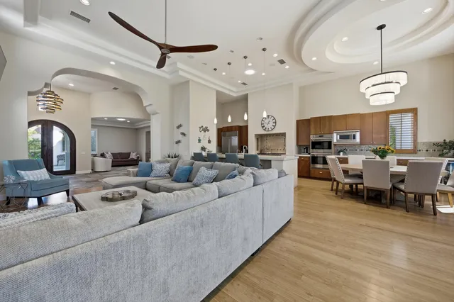 a living room with furniture kitchen view and a chandelier