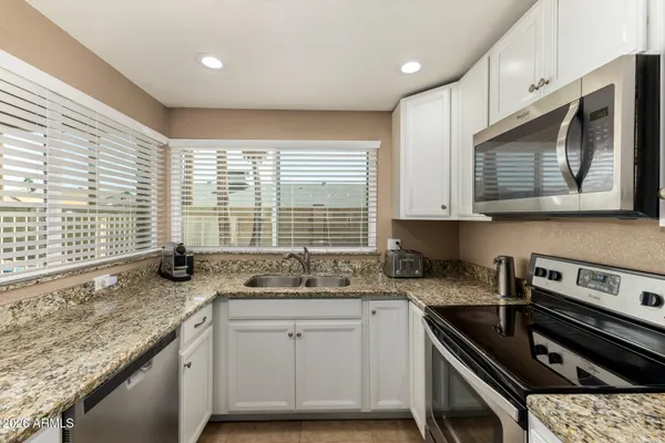 a kitchen with stainless steel appliances granite countertop a sink a stove a microwave and cabinets