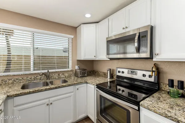a kitchen with granite countertop a stove sink and cabinets