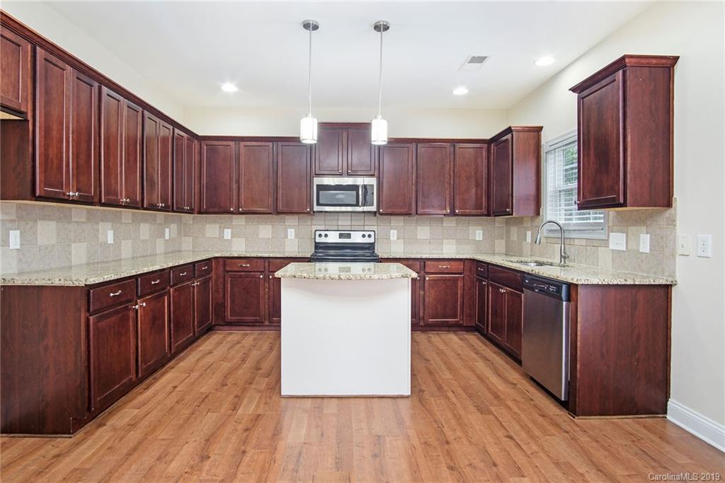 3727 Burnage Hall Road Harrisburg, NC 28075 - Photo 10 of 21 a kitchen with wooden floors wooden cabinets and stainless steel appliances
