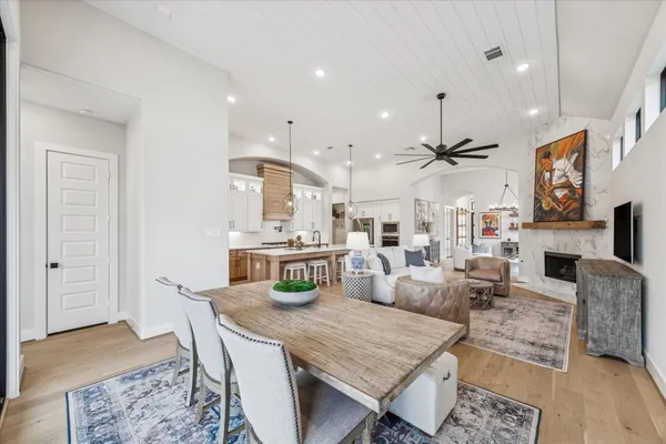 a kitchen with stainless steel appliances kitchen island granite countertop a refrigerator a stove a sink a dining table and chairs with wooden floor