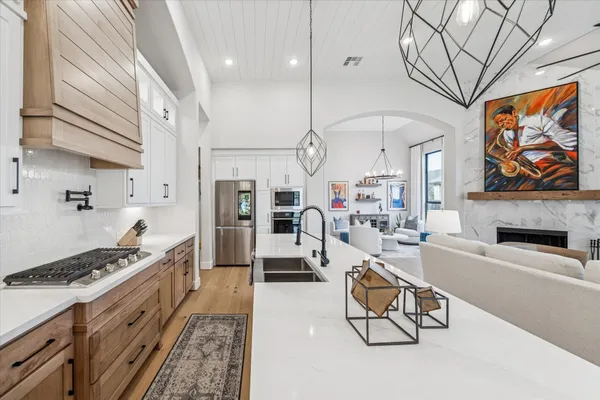 a large white kitchen with a stove a sink dishwasher and a fireplace with wooden floor