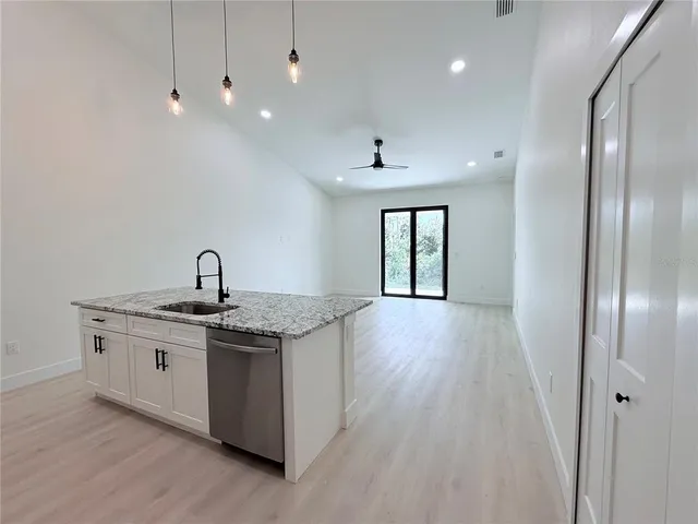a kitchen with stainless steel appliances granite countertop a sink a stove and a wooden floors