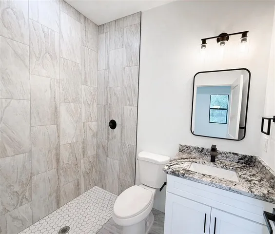 a bathroom with a granite countertop sink mirror vanity and toilet