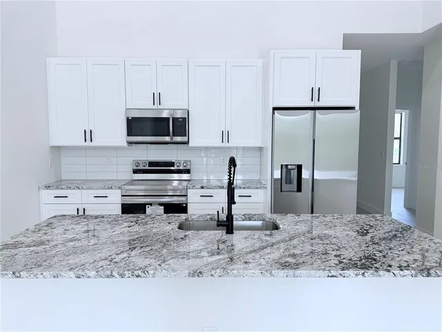 a kitchen with stainless steel appliances granite countertop a stove a refrigerator and a sink