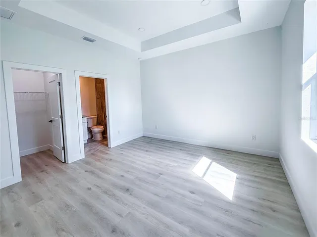 an empty room with wooden floor and windows