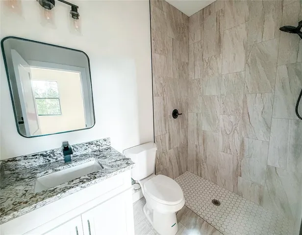 a bathroom with a granite countertop sink toilet and shower