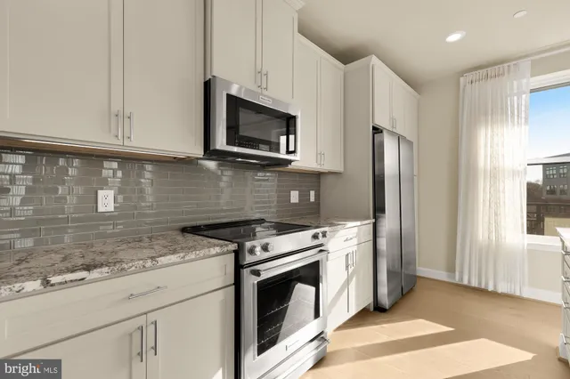 a kitchen with stainless steel appliances granite countertop white cabinets and a stove a oven with white countertops