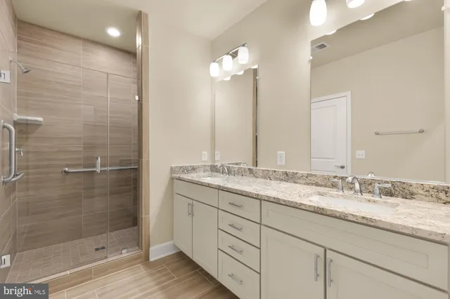 a bathroom with a granite countertop sink a mirror and a shower