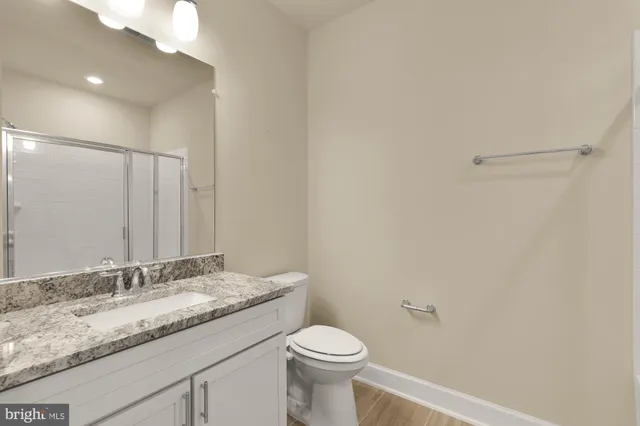 a bathroom with a granite countertop sink a toilet and a mirror