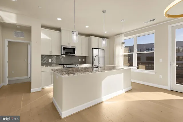a large kitchen with kitchen island granite countertop a large counter top stainless steel appliances and cabinets