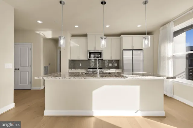 a large kitchen with kitchen island a large counter top appliances and cabinets