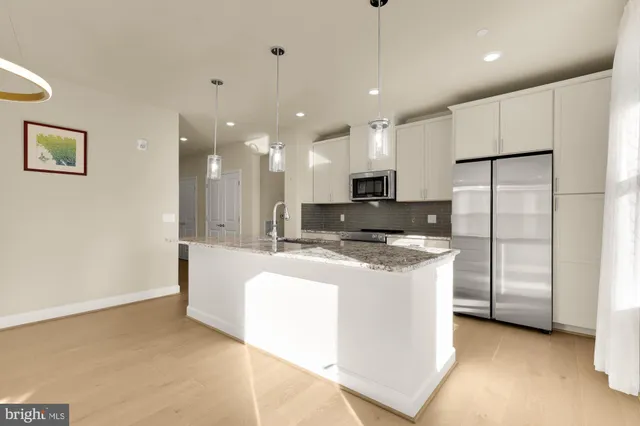 a large kitchen with stainless steel appliances granite countertop a sink a stove and a refrigerator