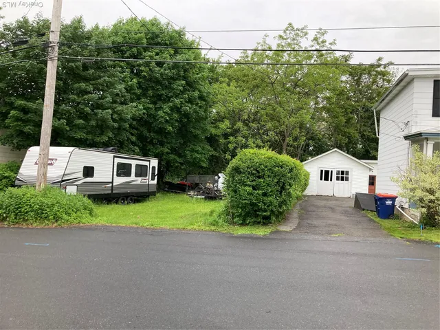 a couple of cars parked in front of a house with yard and green space
