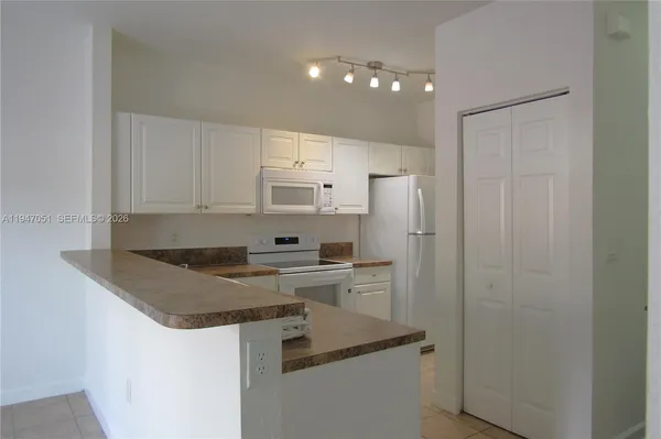 a kitchen with stainless steel appliances granite countertop a refrigerator a stove and white cabinets