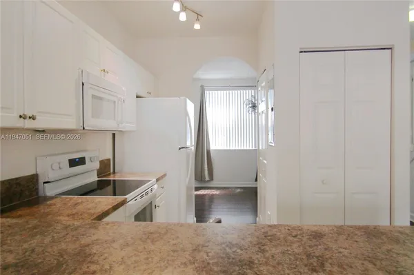 a kitchen with granite countertop white cabinets and white appliances
