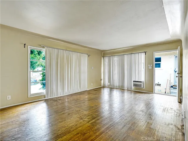 an empty room with wooden floor and windows with curtains view