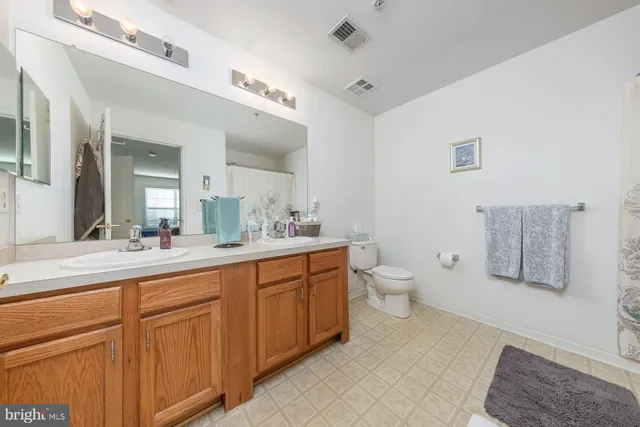 a spacious bathroom with a double vanity sink a toilet and a mirror