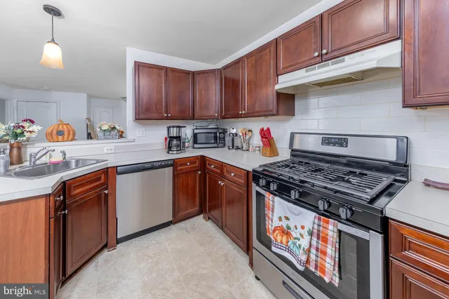 a kitchen with stainless steel appliances granite countertop a stove a sink dishwasher and cabinets with wooden floor