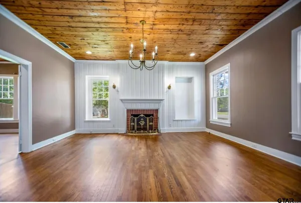 a view of an empty room with wooden floor fireplace and a window