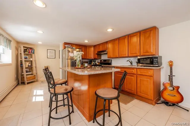 a kitchen with stainless steel appliances granite countertop a stove a sink a refrigerator and chairs