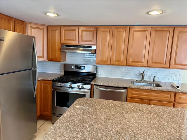 a kitchen with stainless steel appliances granite countertop a refrigerator a stove a sink and dishwasher